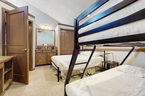 Een hotelkamer met stapelbedden, een houten bureau, een spiegel en een kast.