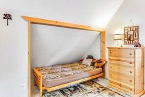A small bedroom with a single bed, a wooden dresser, and a slanted ceiling. - Alpine 3BR with fenced yard, hot tub, & Ping-Pong (Leavenworth)