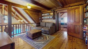A wooden interior with a lofted sleeping area, a sofa, a chest of drawers, and a bookshelf. - Unique 2BR Lakefront - Hot Tub - Dock - Deck (Chelan)