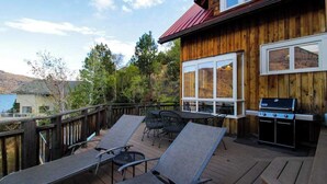 A wooden deck with lounge chairs and a grill, overlooking a mountainous landscape. - Unique 2BR Lakefront - Hot Tub - Dock - Deck (Chelan)