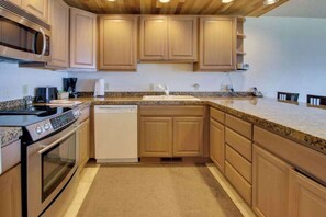 A kitchen with wooden cabinets, a microwave, an oven, a dishwasher, and a granite countertop. - 2BR Lakefront - Pool - Tennis - Hot Tub - Balcony (Chelan)