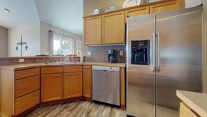 Eine moderne Küche mit Holzschränken, einem Edelstahlkühlschrank und einem Geschirrspüler.
