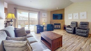 Ein Wohnzimmer mit einer Couch, Sesseln, einem Couchtisch, einem Kamin und einem Fernseher.