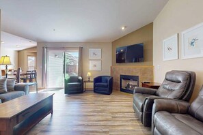 A living room with a fireplace, leather sofas, a television, and a dining area with a table and chairs. - 3BR Mountainview - Patio - Garage Parking - W&D (East Wenatchee)