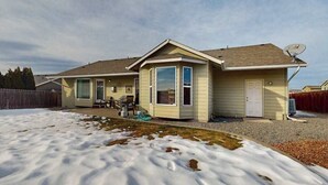 Ein eingeschossiges Haus mit einer überdachten Terrasse, einer Satellitenschüssel und einer Eingangstür.