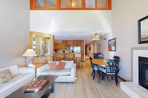 A modern living room with a sofa, coffee table, and a dining area with chairs and a table. - 1BR Lakefront - Pool - Hot Tub - Dock - Tennis (Chelan)