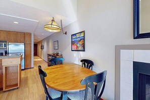 Une cuisine moderne avec des meubles de rangement en bois, une table à manger avec des chaises et un luminaire suspendu.