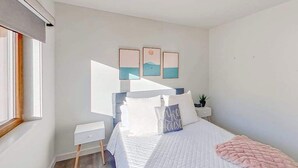 Ein Schlafzimmer mit Bett, Nachttischen, einer Ablagefläche und Wandbildern.