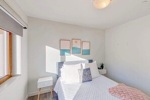 Ein Schlafzimmer mit Bett, Nachttischen, einer Ablagefläche und Wandbildern.