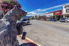 Eine Straße mit einer großen Pferdestatue, parkenden Autos und Geschäften, darunter eine Pizzeria.