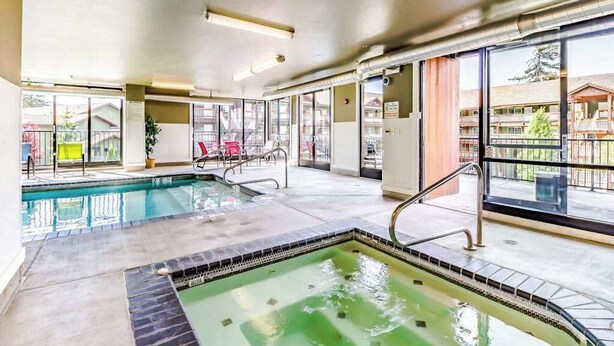Ein Innenpool mit klaren Glaswänden, ein separater Whirlpoolbereich und ein Blick ins Freie.