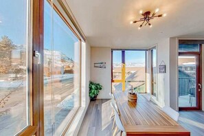 A modern interior with large windows, a wooden table, and a ceiling light fixture. - 2BR Mountainview 2nd-Floor - Balcony - Pool (Chelan)