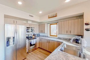A modern kitchen with stainless steel appliances, wooden cabinets, and a granite countertop. - 2BR Mountainview 2nd-Floor - Balcony - Pool (Chelan)