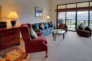 A living room with a sofa, armchairs, a coffee table, a lamp, a radio, and a rug. - 1BR Lakeview 2nd-Floor - Balcony - Pool (Chelan)