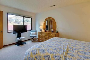A bedroom with a bed, a television, a dresser, a chair, and a large window. - 1BR Lakeview 2nd-Floor - Balcony - Pool (Chelan)