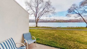 Ein Balkon mit zwei gestreiften Stühlen mit Blick auf einen See und Berge.