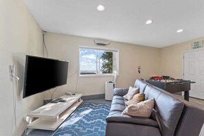 Ein Wohnzimmer mit Flachbildfernseher, einer Couch, einem Kicker und einem Fenster mit Blick.