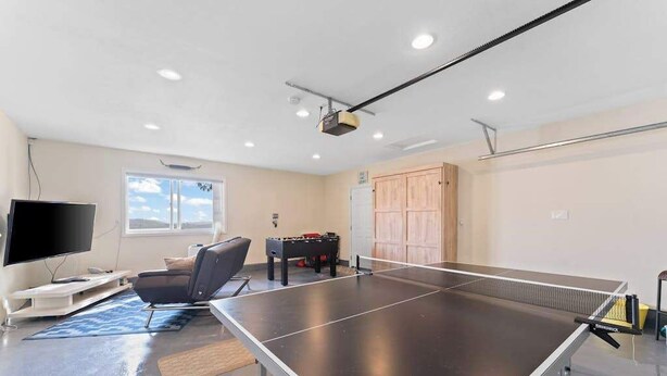 Um quarto com mesa de pingue-pongue, televisão, sofá e mesa de futebol de mesa.
