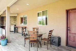 An outdoor patio with a round glass table and chairs, a stone wall, and a door. - 4BR Mountainview Dog Friendly - Chef's Kitchen (Orondo)