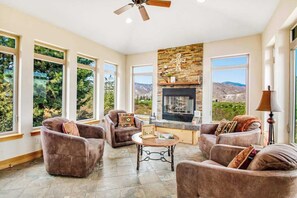A spacious living room with a fireplace, comfortable seating, and large windows offering a view of the outdoors. - 4BR Mountainview Dog Friendly - Chef's Kitchen (Orondo)