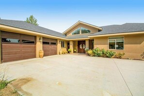 A two-story house with a garage, a covered entryway, and a front yard with landscaping. - 4BR Mountainview Dog Friendly - Chef's Kitchen (Orondo)