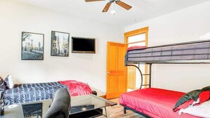 Une chambre avec un lit superposé, un bureau avec une chaise, un téléviseur à écran plat et deux tableaux encadrés au mur.