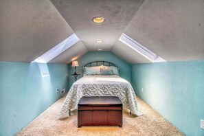 Ein Schlafzimmer mit Bett, einer Bank, einer Lampe und einem Oberlicht.