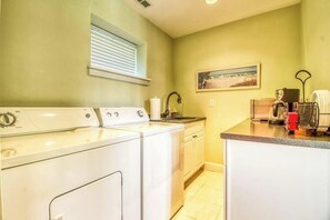 A laundry area with a washing machine, dryer, and countertop with a sink and various items. - Huge 2BR Lakeview - Fireplace - Balcony - W&D (Manson)