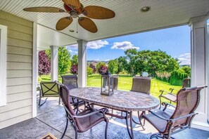 A covered patio with a round table and chairs, a ceiling fan, and a view of a well-maintained lawn and trees. - Huge 2BR Lakeview - Fireplace - Balcony - W&D (Manson)