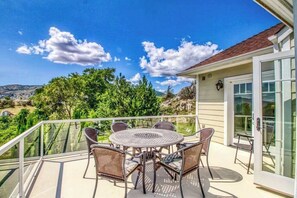 Ein Balkon mit rundem Tisch und Stühlen mit Blick auf eine Berglandschaft.