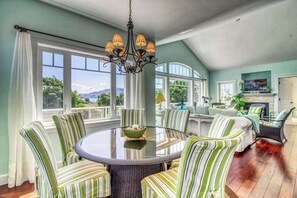 A dining area with a round table and striped chairs, a chandelier, and large windows with a view. - Huge 2BR Lakeview - Fireplace - Balcony - W&D (Manson)