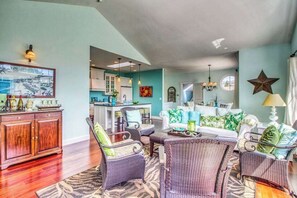 A spacious living room with wicker furniture, a dining area with a table and chairs, and a kitchen in the background. - Huge 2BR Lakeview - Fireplace - Balcony - W&D (Manson)