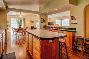 A kitchen with wooden cabinets, a large island, and bar stools. - 3BR Lakefront - Dock - Deck - Firepit - W&D (Manson)