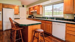 Una cocina con armarios de madera, un refrigerador blanco, un microondas, un lavavajillas y una ventana con vista al exterior.