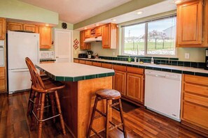 A kitchen with wooden cabinets, a white refrigerator, a microwave, a dishwasher, and a window with a view of the outdoors. - 3BR Lakefront - Dock - Deck - Firepit - W&D (Manson)