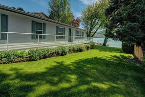 A single-story mobile home with a fenced yard and a view of a lake.