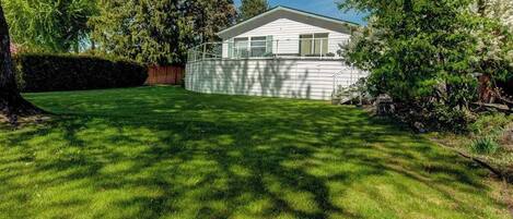 A residential property with a well-maintained lawn, a detached house with a gabled roof, and a wooden fence.