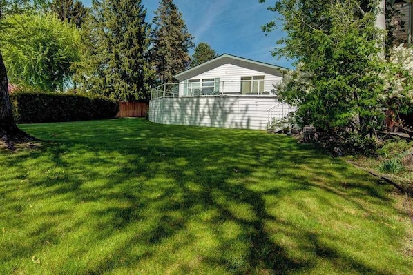 A residential property with a well-maintained lawn, a detached house with a gabled roof, and a wooden fence.