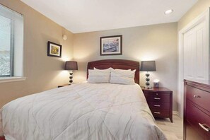 A bedroom with a large bed, two bedside tables with lamps, a dresser, and a framed picture on the wall. - Luxe 1BR Lakeview - Patio - Pool - (Chelan)
