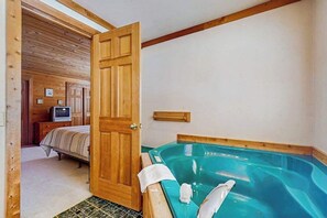 A room with a wooden door, a bed, a small television, and a hot tub. - Spacious 3BR Mountainview - Fireplace - Deck (Leavenworth)