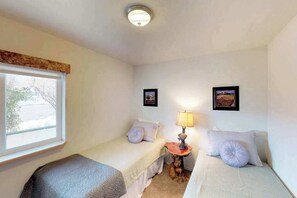 Una habitació amb dos llits individuals, una taula petita amb una làmpada i dos quadres a la paret.