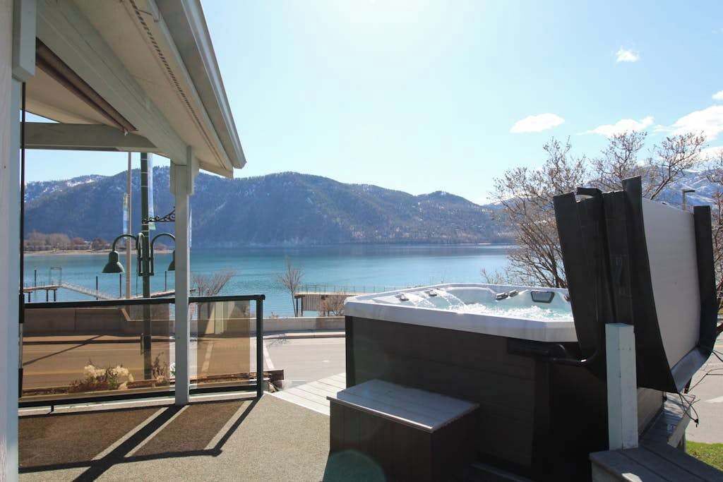 A hot tub on a balcony with a view of a lake and mountains.