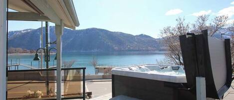 A hot tub on a balcony with a view of a lake and mountains.