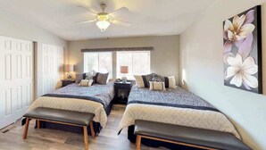 Ein Schlafzimmer mit zwei Betten, einem Deckenventilator und einem großen Blumenbild an der Wand.