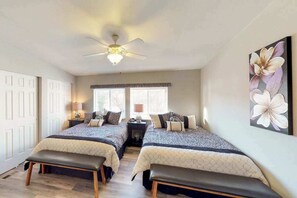 Ein Schlafzimmer mit zwei Betten, einem Deckenventilator und einem großen Blumenbild an der Wand.