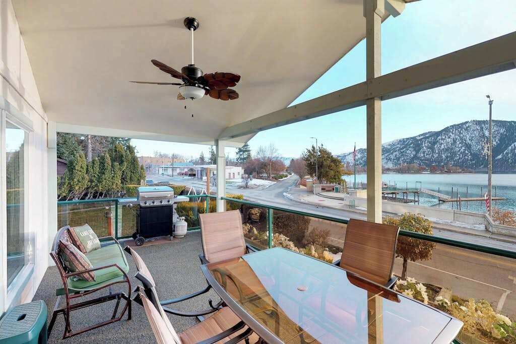 Un balcon avec des sièges, un ventilateur de plafond et une vue sur un pont et une étendue d’eau.