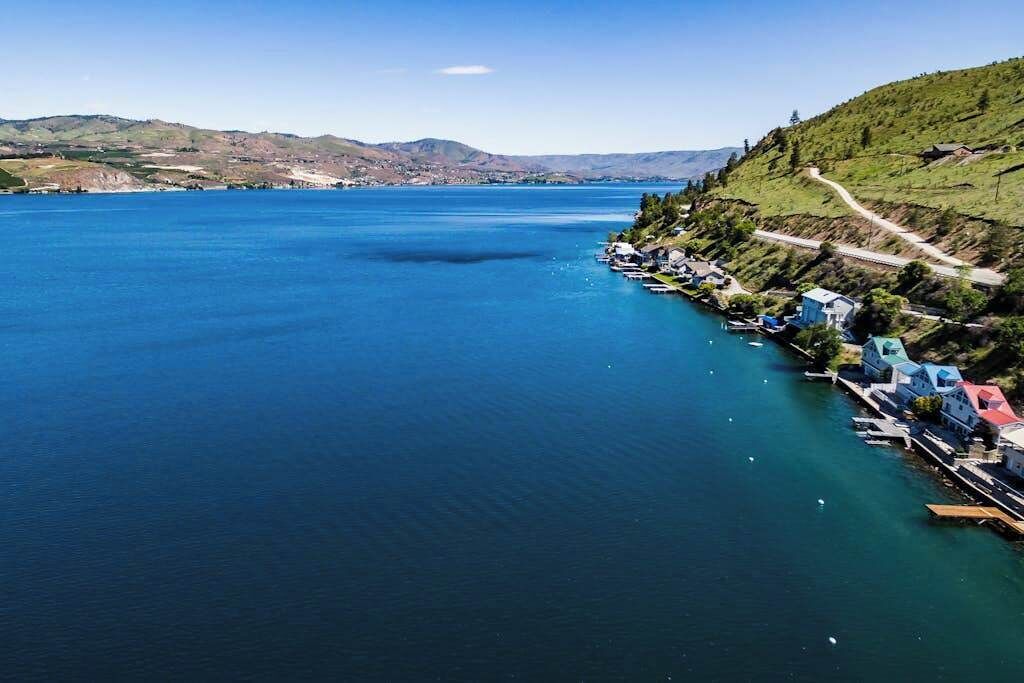 Un pueblo costero con un puerto deportivo, barcos y casas a lo largo de la costa.