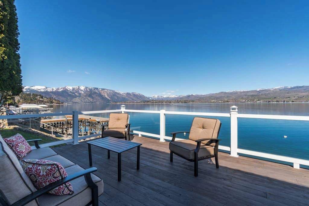 Una terraza con asientos y vista a un lago y montañas.