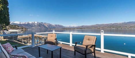 Une terrasse avec des sièges et une vue sur un lac et des montagnes.