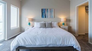 Quarto com uma cama grande, duas mesas de cabeceira, uma obra de arte na parede e uma janela.